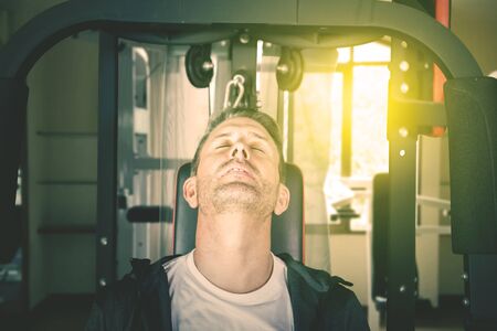 Caucasian man looks asleep while sitting on the exercise machine. Shot in the gym centerの写真素材
