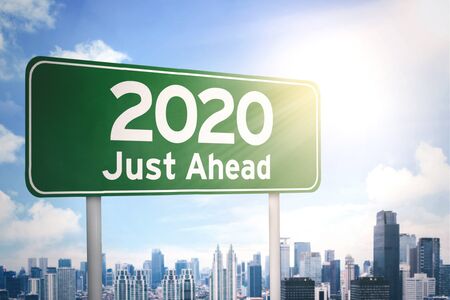 Close up of a green signboard with a text of 2020 just ahead under sunlight