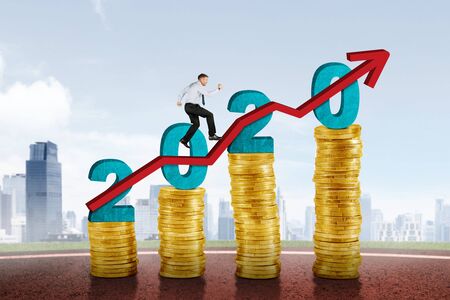 Caucasian businessman running above upward arrow with stacks of gold coins and number 2020