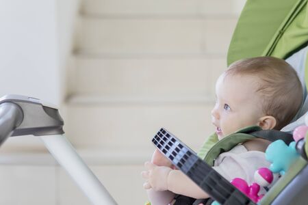 Side view of Caucasian baby girl looks happy while sitting in the stroller