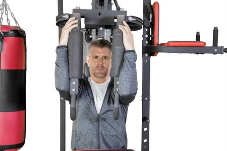 Caucasian man looking at the camera while exercising with a fitness machine in the studio