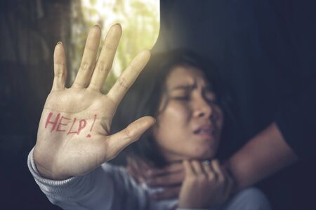 Photo of Asian woman showing her hand with a help text choked by her husband. Domestic violence...