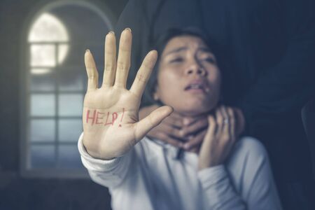 Domestic violence concept  of Asian woman showing her hand with a help text choked by her husband.の写真素材