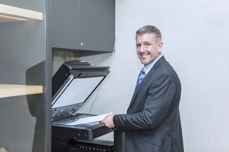 Caucasian businessman using photocopy machine in office
