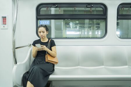 Asian woman using mobile phone in jakarta LRT Trainの写真素材