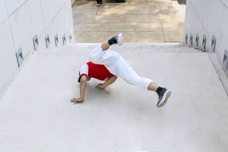 Overweight Street Bboy dancer wearing hat doing handstand on staircase outdoorの写真素材