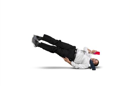 Businessman looking at his smart phone while falling isolated over white backgroundの写真素材