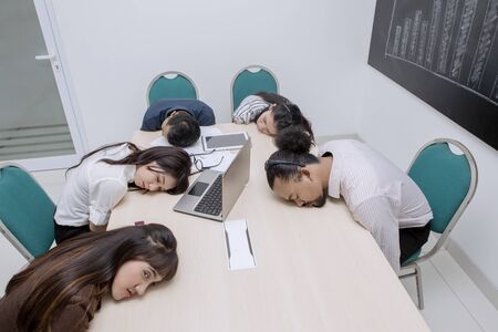 Five multiethnic people sleeping while working in their officeの写真素材