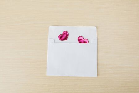 Top view of an envelope filled with two red love stickers on table background. Valentine's day or...
