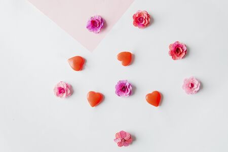 Top view of flower papers and love candies shaped like an arrow, isolated in white background with...