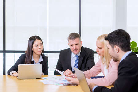 Portrait of multiethnic employees showing business reports to the Caucasian businessman while...