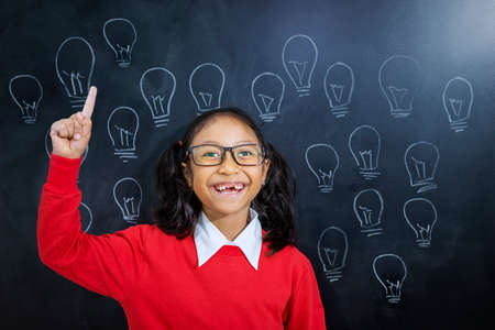 Portrait of an adorable Asian girl wearing school uniform while realizing an idea in a classroomの写真素材