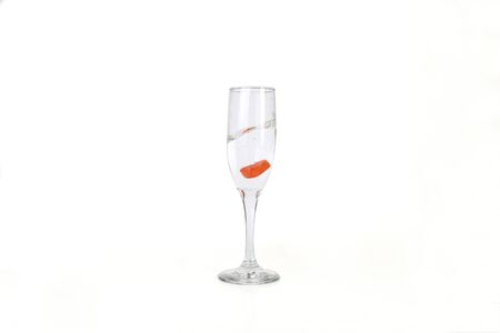 Glass of water filled with heart shaped candy, isolated in white backgroundの写真素材