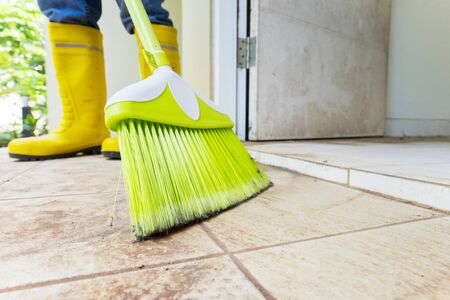 Low angle closeup shot of a male worker cleaning the floor with a broomの写真素材