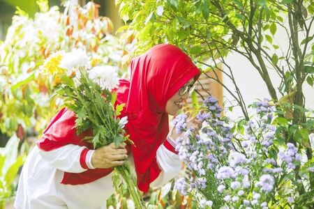 Happy senior muslim woman kissing flowers in the backyard gardenの写真素材