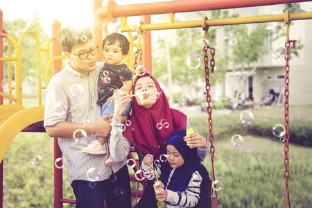 Happy muslim family blowing bubbles playing in the parkの写真素材