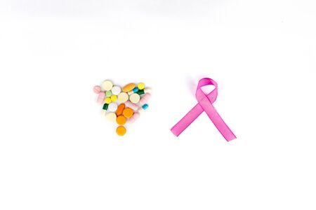 Flat layout of a pink ribbon besides heart shaped pills, isolated in white backgroundの写真素材