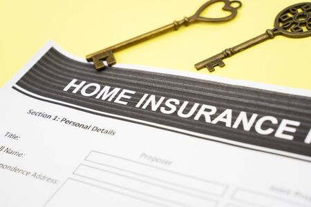 Closeup of home insurance document paper near some old keys, isolated in yellow backgroundの写真素材