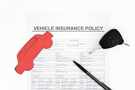 Flat layout of vehicle insurance policy beneath a pen, red car shaped cardboard, and key car;...