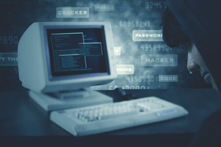 Picture of unknown man sitting in front of computer and keyboard with binary code on screen