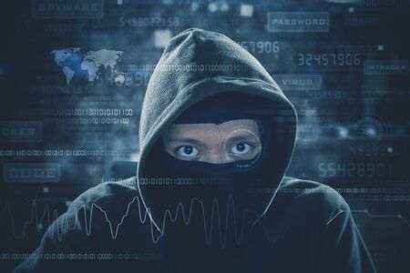Hacker working with mask and looking at binary code during attacking internet systemの写真素材