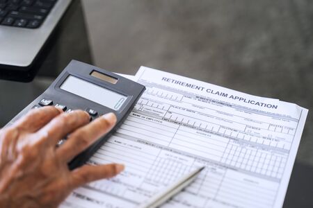 Senior man hand using calculator with retirement application form on the table