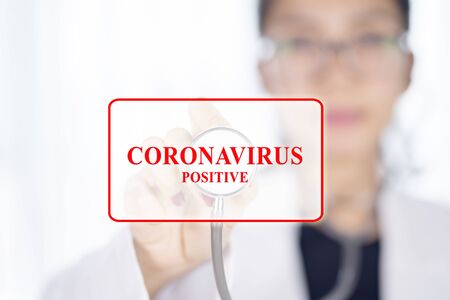 Picture of female doctor using stethoscope with coronavirus positive text, with blurred background, isolated on white backgroundの写真素材