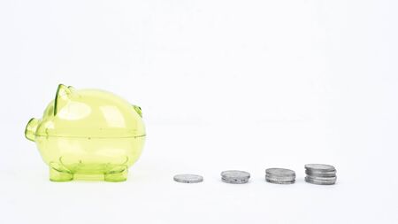 Piggy bank and pile of coins shaped financial chart in the studio, isolated on white background