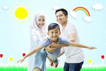 Portrait of muslim parents swinging cute child on their hands while looking at cameraの写真素材