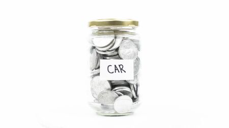 Jar full of coins with a car text symbolizing savings to buy a car, isolated on white backgroundの写真素材