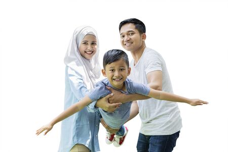 Portrait of little boy swinging on his hands parents while looking at camera, isolated on white backgroundの写真素材