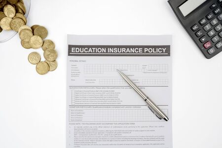 Top view of education insurance policy with coins and calculator on the tableの写真素材