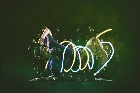 Young man break dancing with light effect at night on the streetの写真素材