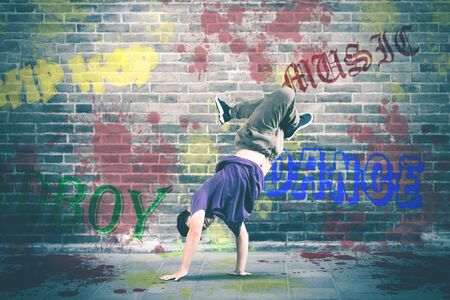 Picture of hip hop dancer doing handstand while showing freestyle, bricks wall backgroundの写真素材