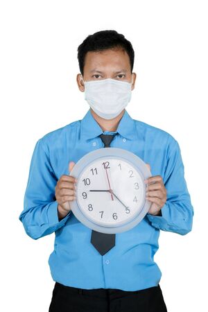 Portrait of unidentified man wearing a blue suit and face mask while holding a clock, isolated in white backgroundの写真素材