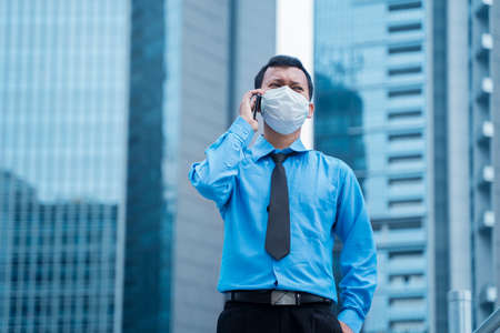 JAKARTA - Indonesia. May 12, 2020: Young businessman wearing a mask and making a phone call while...