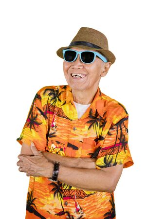 Happy old man wearing sunglasses and summer clothes while standing in the studio, isolated on white backgroundの写真素材