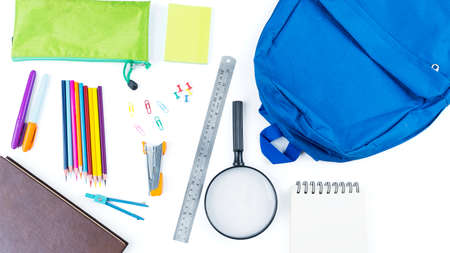 Top down view of blue backpack with surrounded by school supplies on the table. Isolated on white...