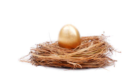 Close up of a shiny golden egg on the straw nest. Isolated on white backgroundの写真素材