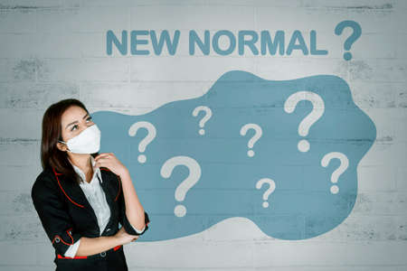 Female manager wearing a medical mask while using a laptop and standing in the studio. Isolated on white backgroundの写真素材
