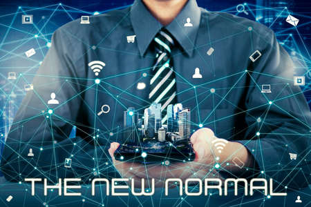 Side view of delivery man wearing face mask and gloves while carrying a stack of packages and standing near an opened door of customer houseの写真素材