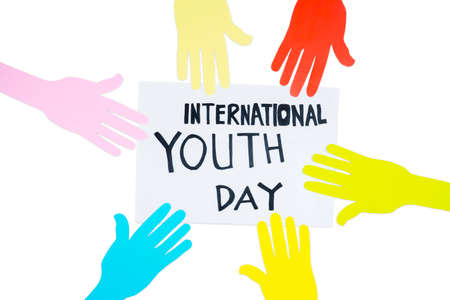Top view of colorful paper hands with text of International Youth Day on the paper above table with white backgroundの写真素材