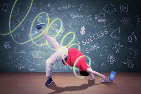 Asian man doing freestyle while performing break dance in the studio with green screen background