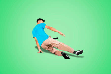Asian man doing freestyle while performing break dance in the studio with green screen backgroundの写真素材