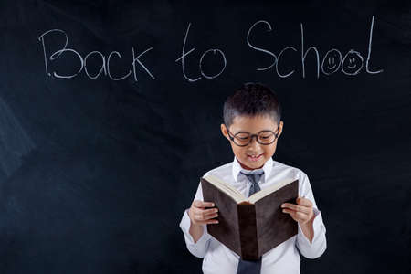 Preteen boy holding a magnifying glass front of his mouth while standing in the classroom
