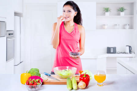 Indian woman using earphone to hear music while working out on exercise bike. Isolated on white backgroundの写真素材