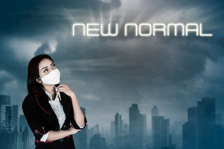 Female manager wearing a medical mask while using a laptop and standing in the studio. Isolated on white backgroundの写真素材