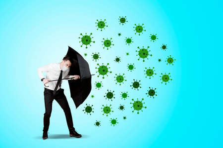 Caucasian businessman wearing a face mask and using umbrella to protect from Coronavirus disease in...