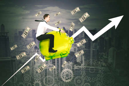 Caucasian businessman riding a piggy bank while flying with banknotes and upward arrow on cityscape...