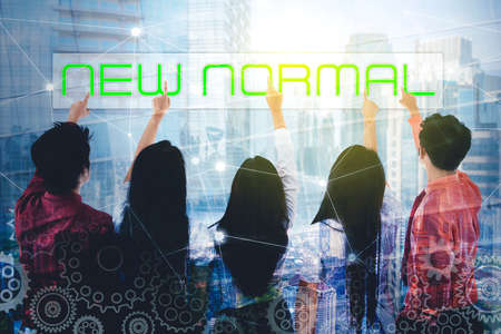 Double exposure of business people touching new normal button on virtual screen with modern city backgroundの写真素材